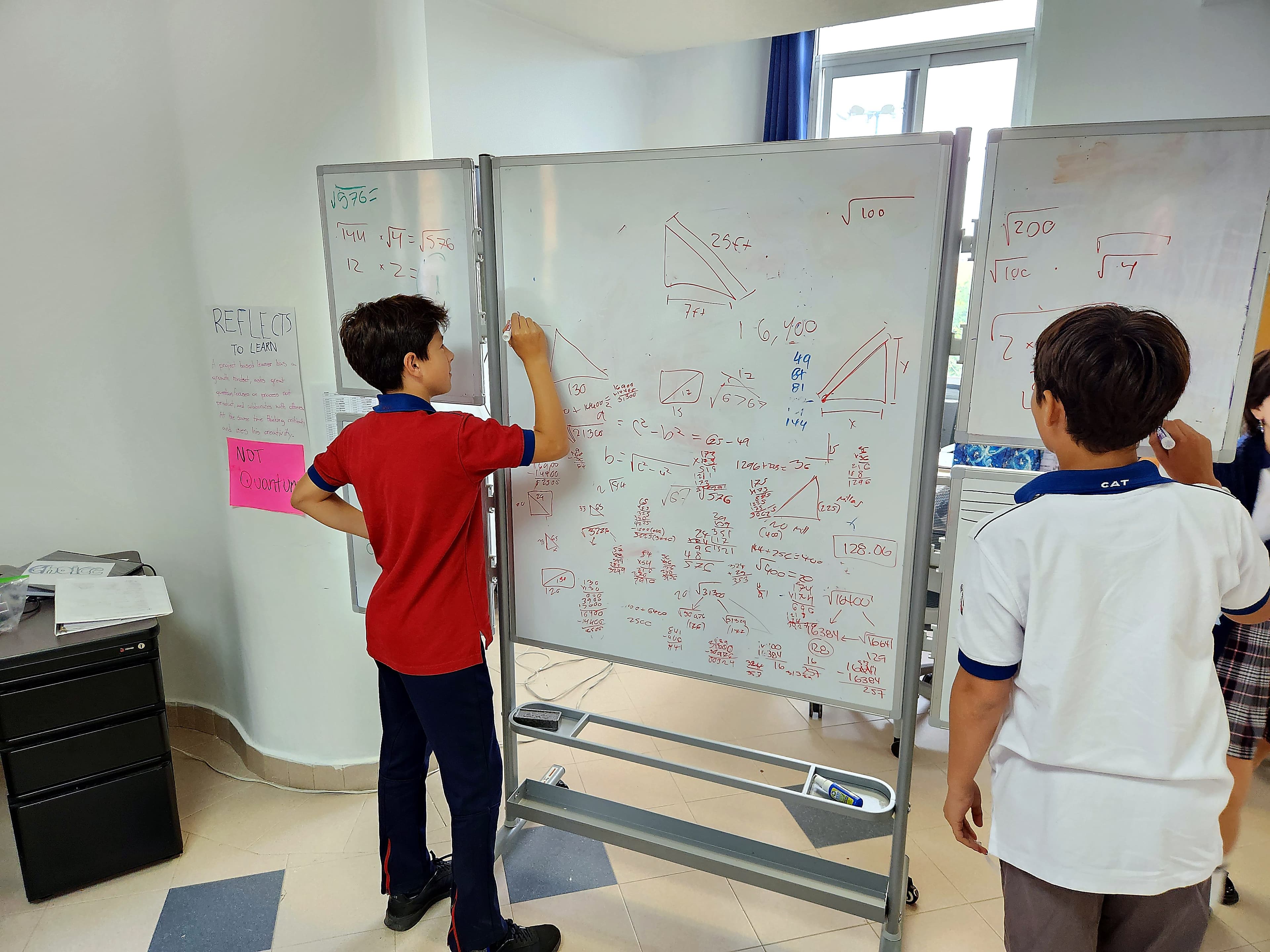 Students gathered around whiteboards during collaborative learning