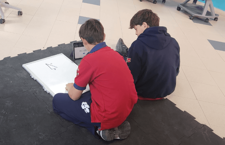 Students solving problems on a whiteboard with the digital system nearby